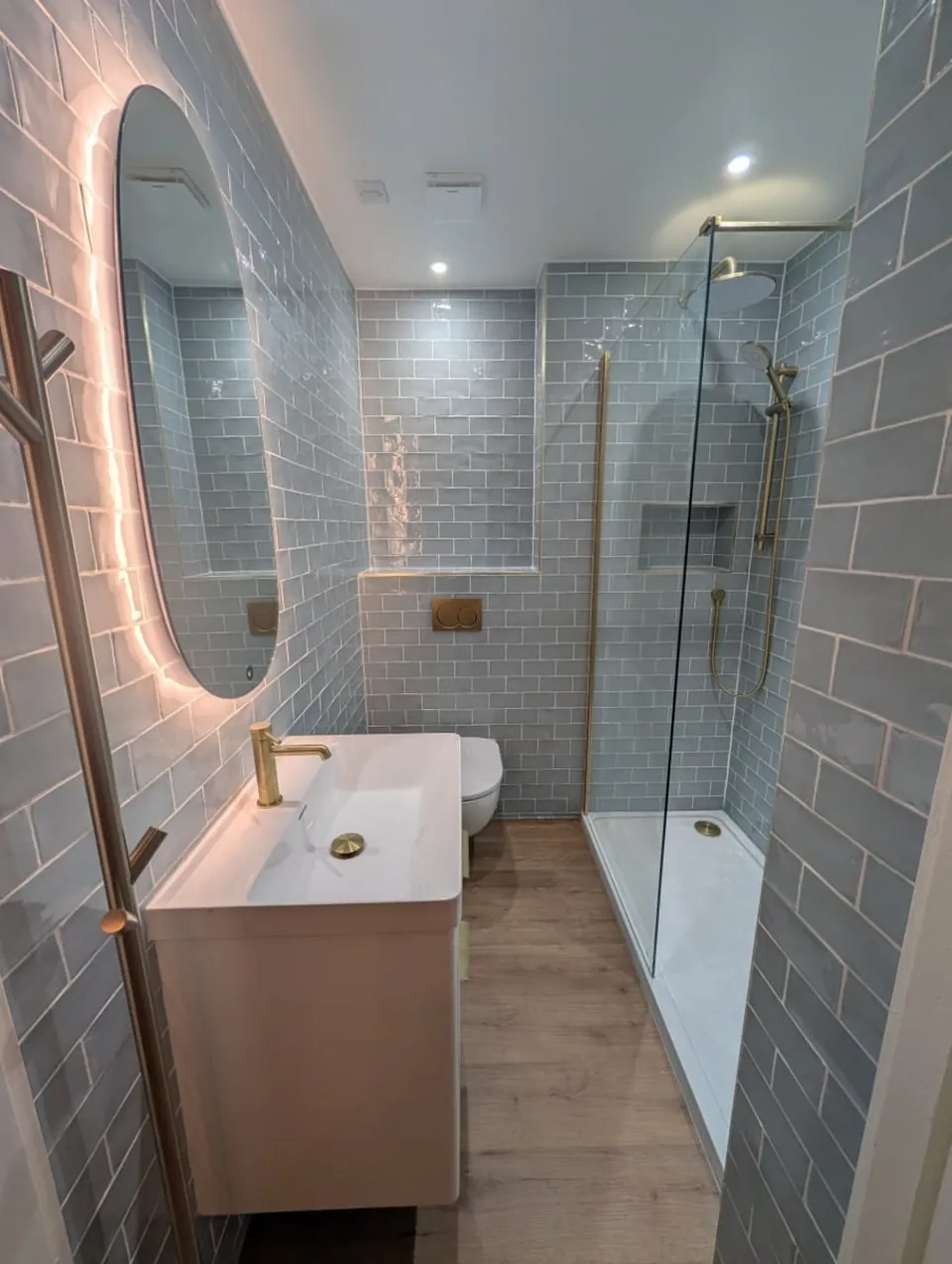 Blue-tiled shower room with vanity storage and illuminated mirror
