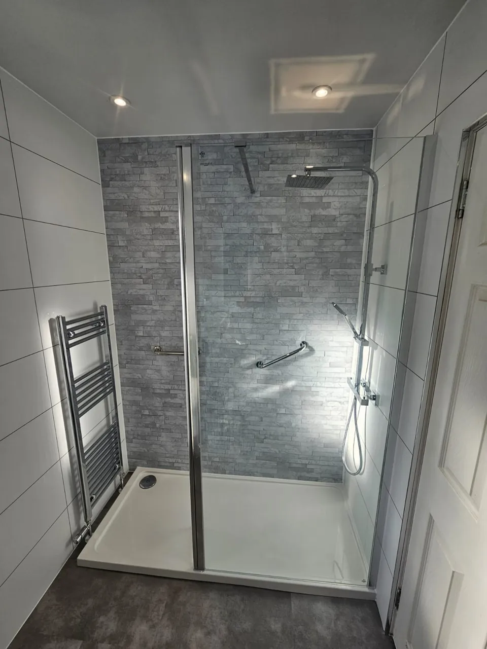 Glass shower enclosure with grey walls and chrome fittings